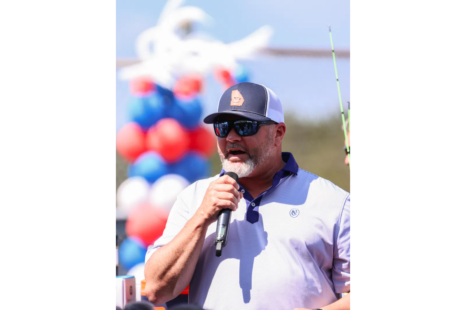 a man wearing sunglasses and a hat holding a microphone