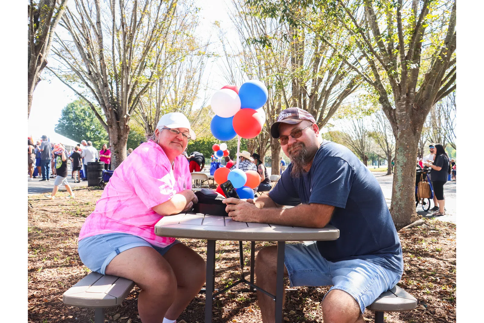 a couple of men sitting at a table with balloons and a laptop