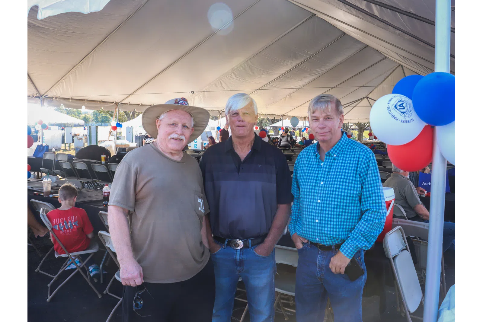 a group of men standing under a tent with balloons