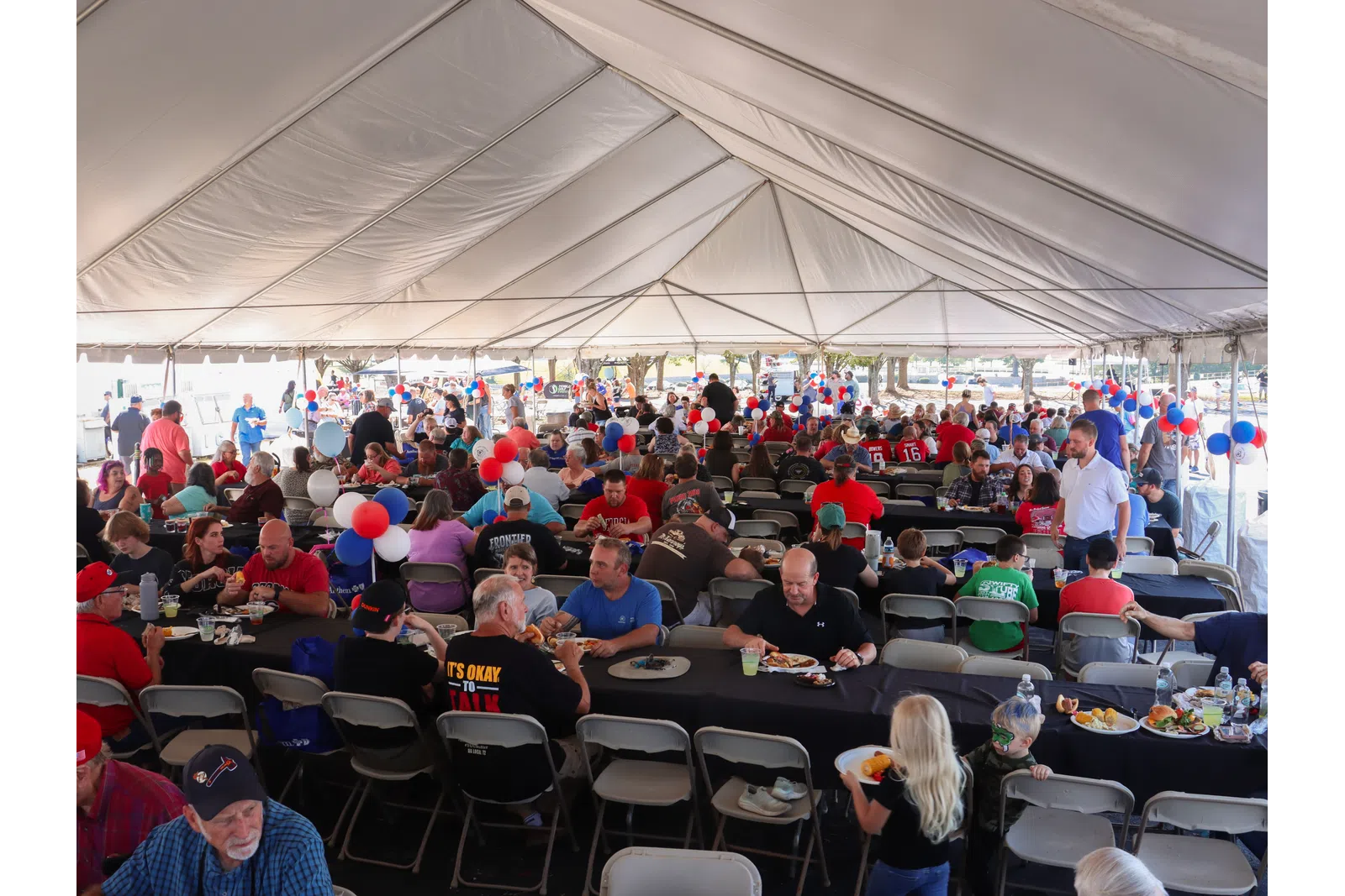 a large crowd of people sitting at tables in a tent