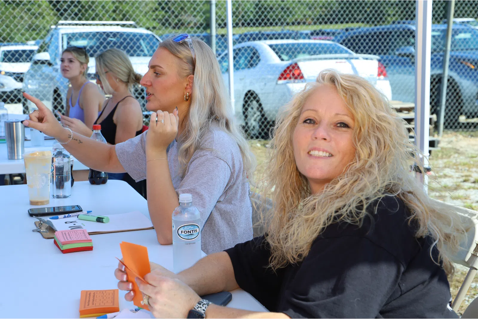 a couple of women sitting at a table with a bottle of water