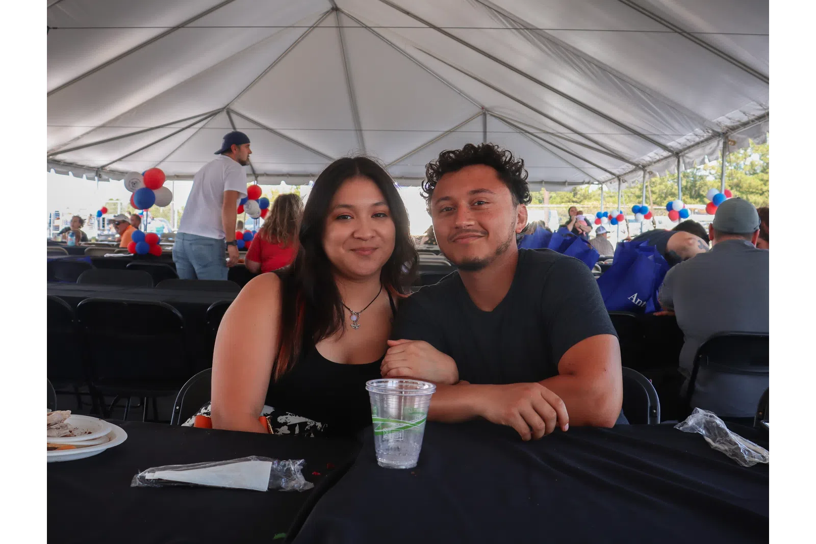 a man and woman sitting at a table under a tent