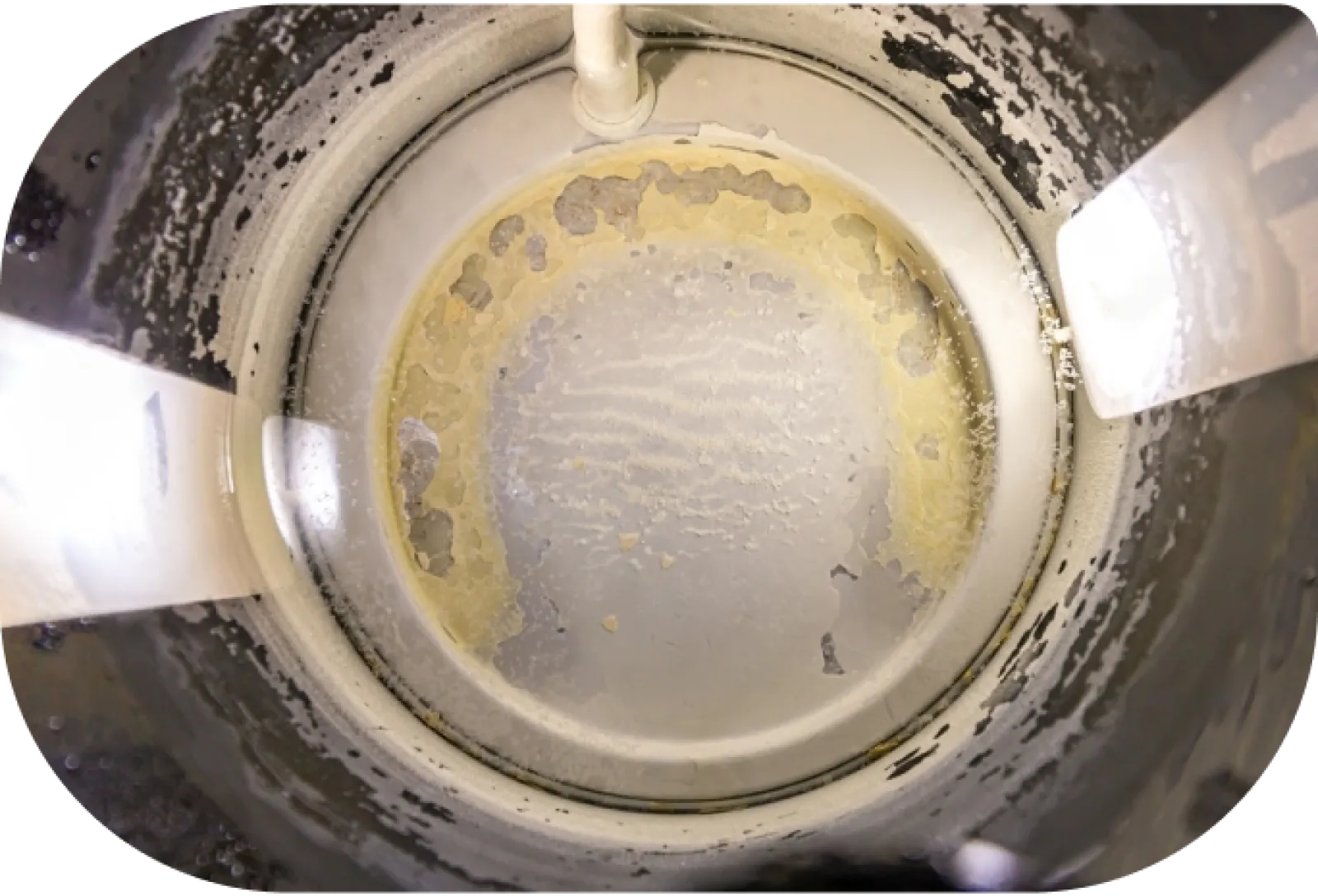 Close-up view inside a metal container with peeling white and yellow paint and light reflections.