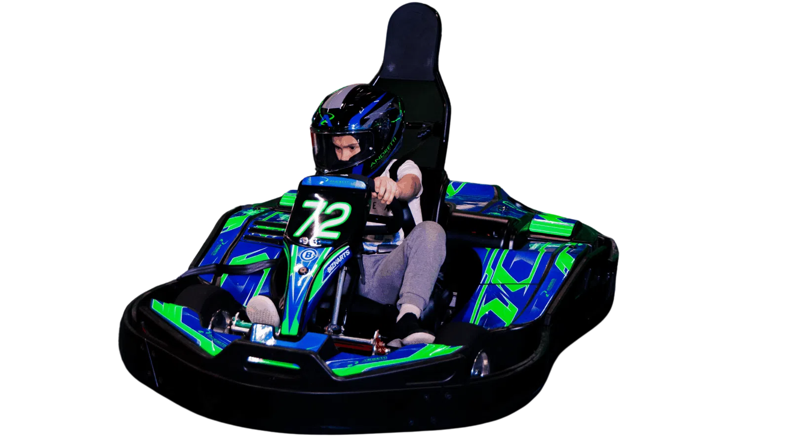 Child wearing helmet driving a blue and green go-kart with number 72 on the front under bright lighting