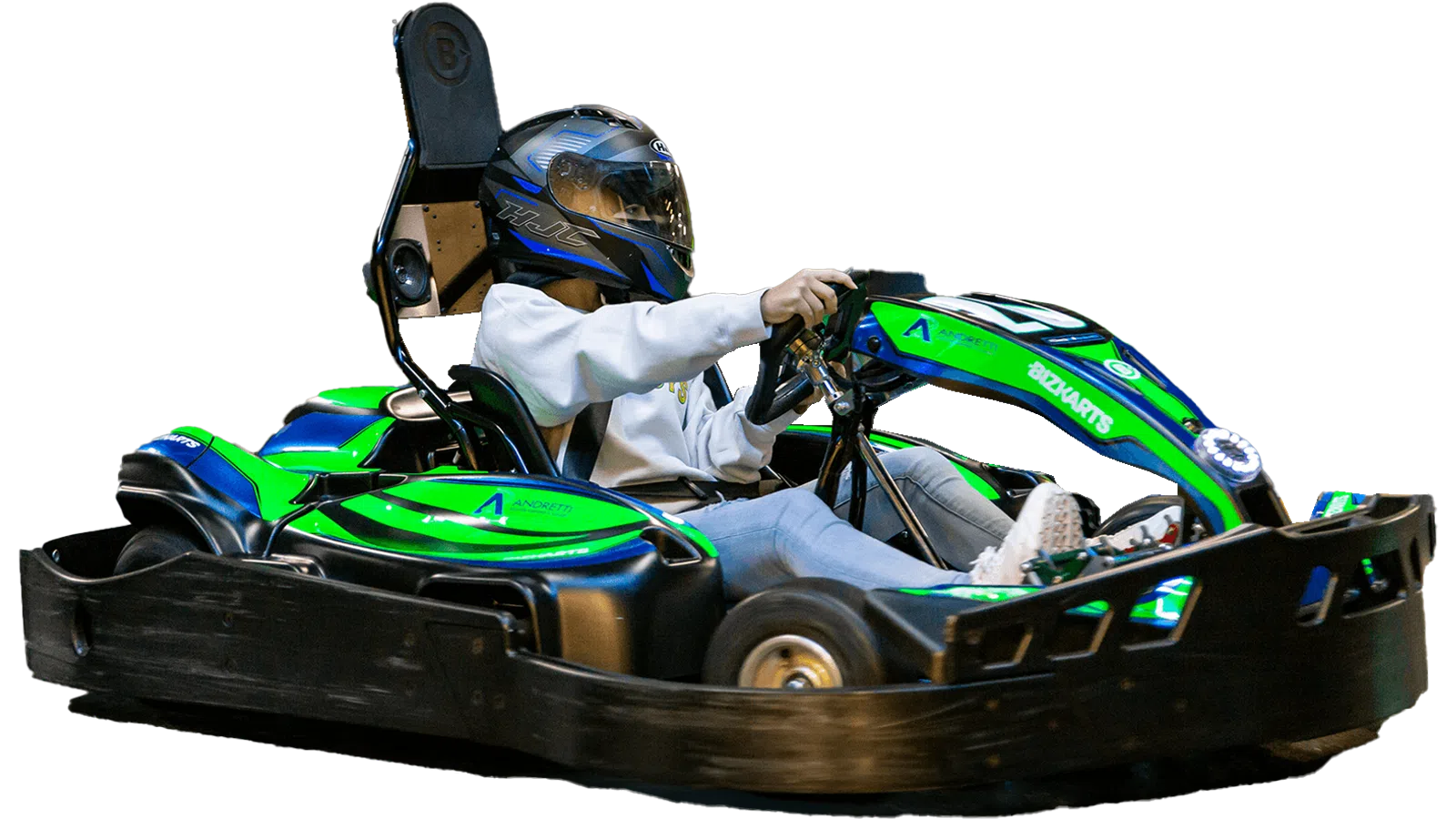 Person wearing helmet driving a green and blue go-kart on a black track isolated on white background.