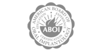 Black and white badge logo of the American College of Oral Implantologists with sun and text in circle.