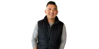 Smiling man wearing a black puffer vest over a gray long-sleeve shirt isolated on white background