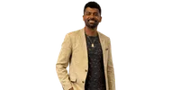 Smiling man wearing a beige blazer over a black patterned shirt with a gold pendant necklace