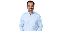 Smiling man with glasses and beard wearing a light blue button-up shirt against a white background