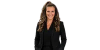 Smiling woman with long wavy hair wearing a black blazer and black top against a transparent background