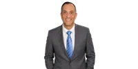 Smiling middle-aged man in gray suit with blue striped tie and white shirt, posing against white background.