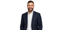 Smiling bearded man in a navy plaid blazer and white button-up shirt against a transparent background