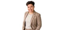 Smiling person with short dark hair wearing a beige blazer and light gray shirt against white background