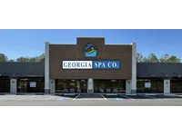 Exterior view of Georgia Spa Co. storefront with signage and clear parking spaces under a blue sky