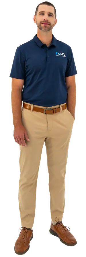 Man wearing navy polo shirt with PV logo, beige pants, brown belt, and brown shoes standing confidently.