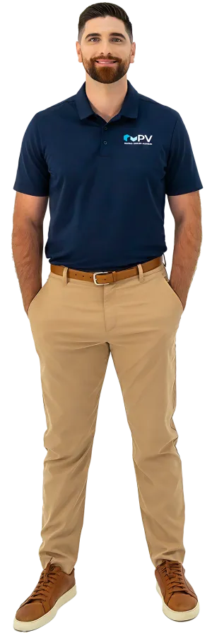 Man wearing navy blue polo with PV logo, beige pants, brown belt, and brown sneakers standing with hands in pockets.