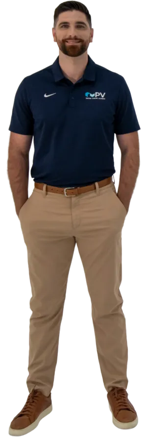 Man in navy polo shirt with PV logo and khaki pants standing with hands in pockets smiling
