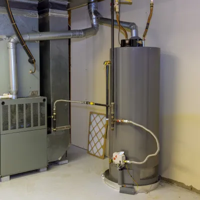 Basement utility area with a furnace and water heater connected by pipes and ventilation ducts.
