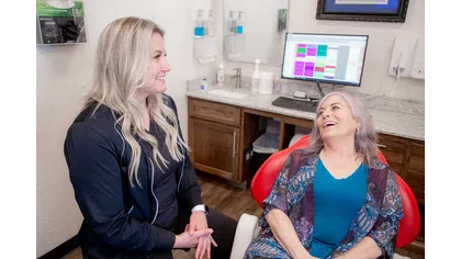 Smiling female dentist or hygienist talking with a happy older female patient in a dental office.