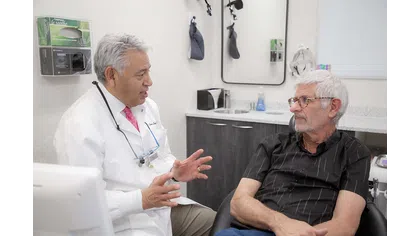 Doctor in white coat discussing treatment with elderly male patient in medical consultation room
