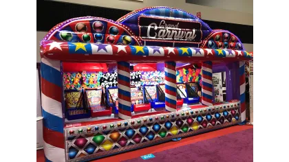 Colorful inflatable Grand Carnival game booth decorated with stars and balls at an indoor event.