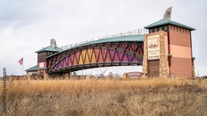 Historic Archway bridge with colorful panels and Americana flag in dry grassland under overcast sky.
