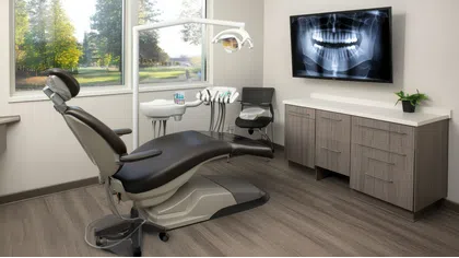 Modern dental office interior with dental chair, equipment, and dental x-ray on the wall.
