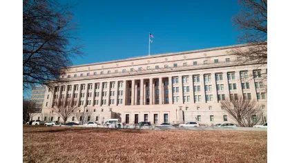The U.S. Department of the Interior building with American flag against a clear blue sky