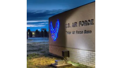 Illuminated U.S. Air Force sign at Tinker Air Force Base at dusk with glowing blue emblem on wall.