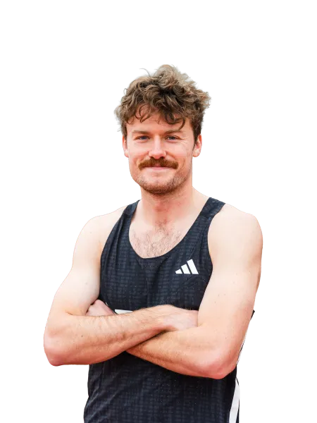 Smiling man with curly hair and mustache wearing black Adidas tank top with arms crossed