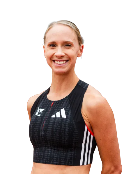 Smiling female athlete wearing a black Adidas sports crop top with white stripes and logo.