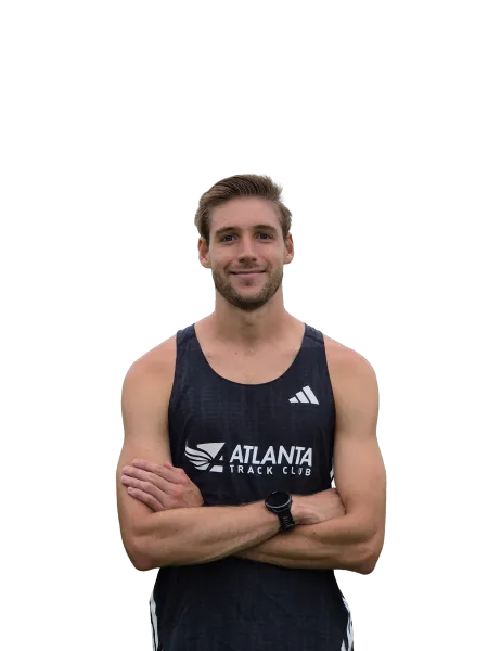 Smiling male athlete in black Atlanta Track Club tank top with arms crossed and smartwatch on wrist.