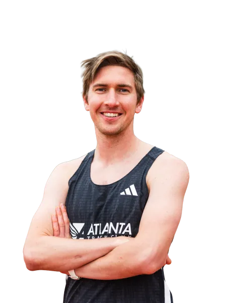 Young male athlete in a black Atlanta Track Club tank top smiling with arms crossed.