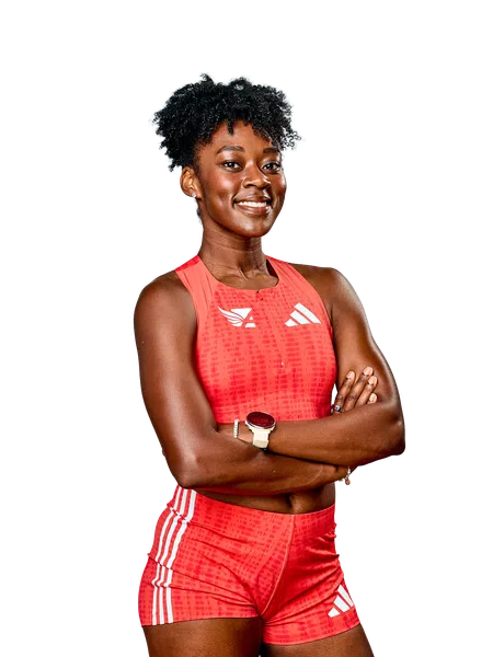 Confident female athlete in red sportswear with arms crossed smiling against black background