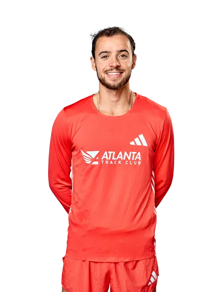 Smiling male athlete wearing red Atlanta Track Club running gear with Adidas logos on top and shorts.