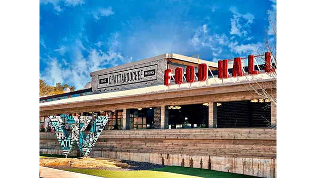 Exterior view of Chattahoochee Food Works Food Hall with clear sky and artistic signage on wooden facade.
