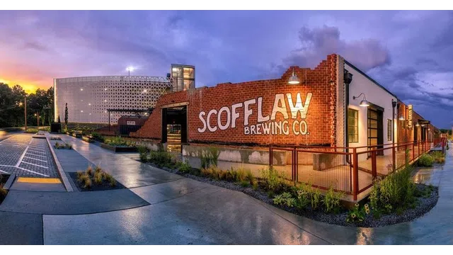 Scofflaw Brewing Co. exterior with brick wall signage and industrial surroundings at sunset.