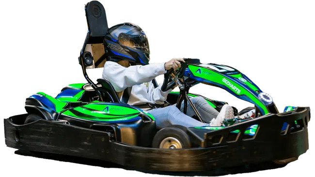 Person wearing helmet driving a green and blue go-kart on a black track isolated on white background.