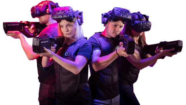 Four people wearing VR headsets and vests aiming laser tag guns with red and purple lighting