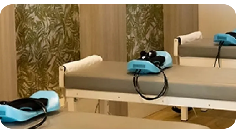 Massage or therapy room with beds and blue electric therapy devices on them in a calming setting.