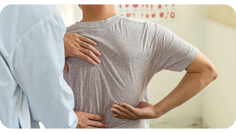 Physical therapist examining patient's back pain with hands on lower and upper back in clinical setting
