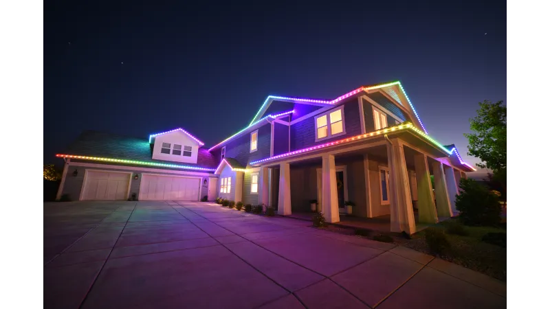 Modern house at night decorated with vibrant multicolor LED lights along the roofline.
