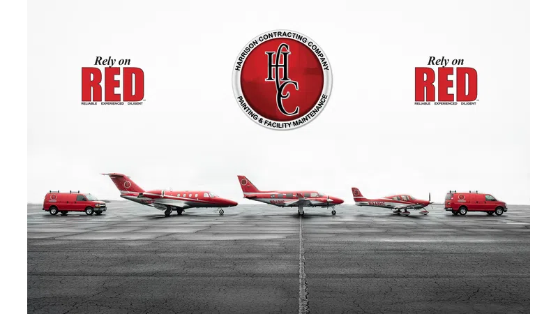 Red aircraft and service vans lined up on tarmac with Harrison Contracting Company logo and Rely on Red text
