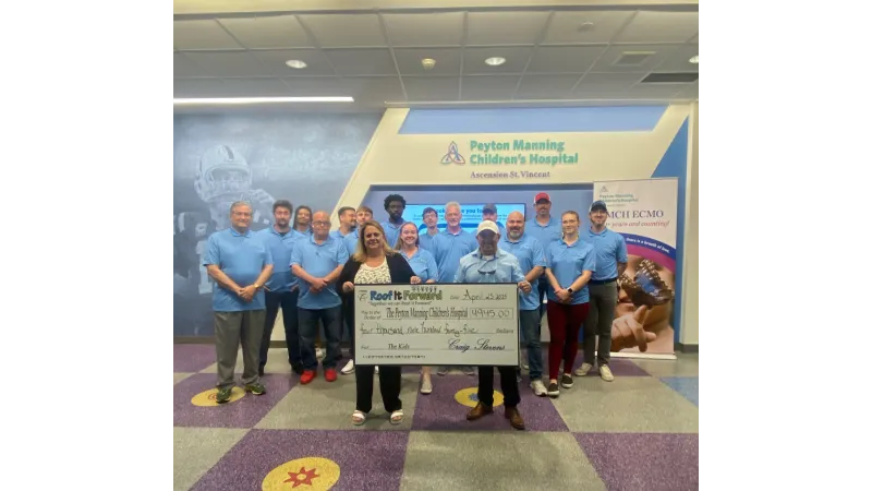 Roof It Forward team holding a large check at Peyton Manning Children's Hospital lobby.