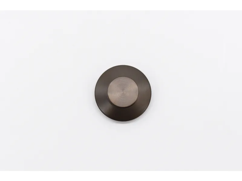 Round dark bronze doorbell button with smooth surface on white background.