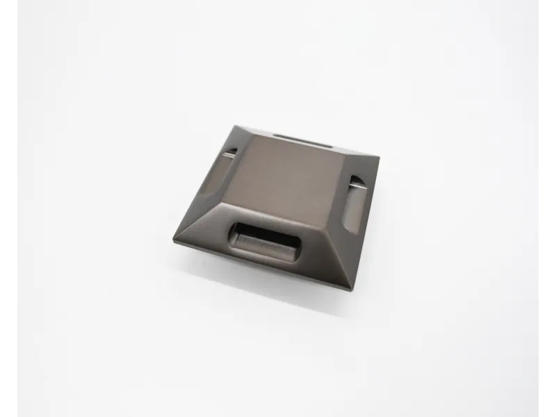 Dark gray square metallic object with angled sides and rectangular cutouts on white background