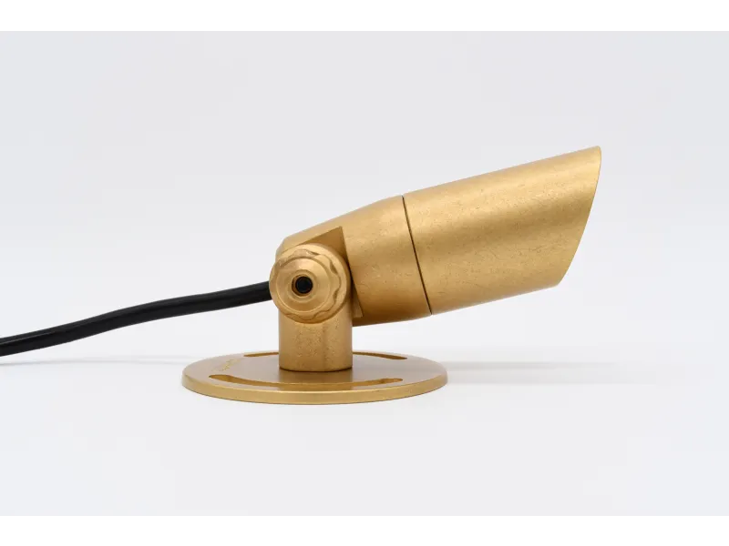 Gold-colored adjustable spotlight or small outdoor light fixture with black cable on white background