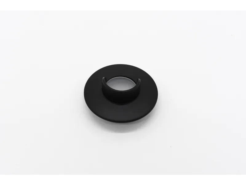 Black circular plastic component with a central hollow cylindrical part on a white surface.
