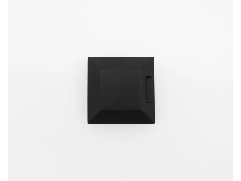 Top view of a small black square box with a drawer handle on a white background.