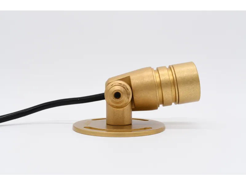 Compact gold-colored adjustable spotlight with black cord mounted on round base against white background
